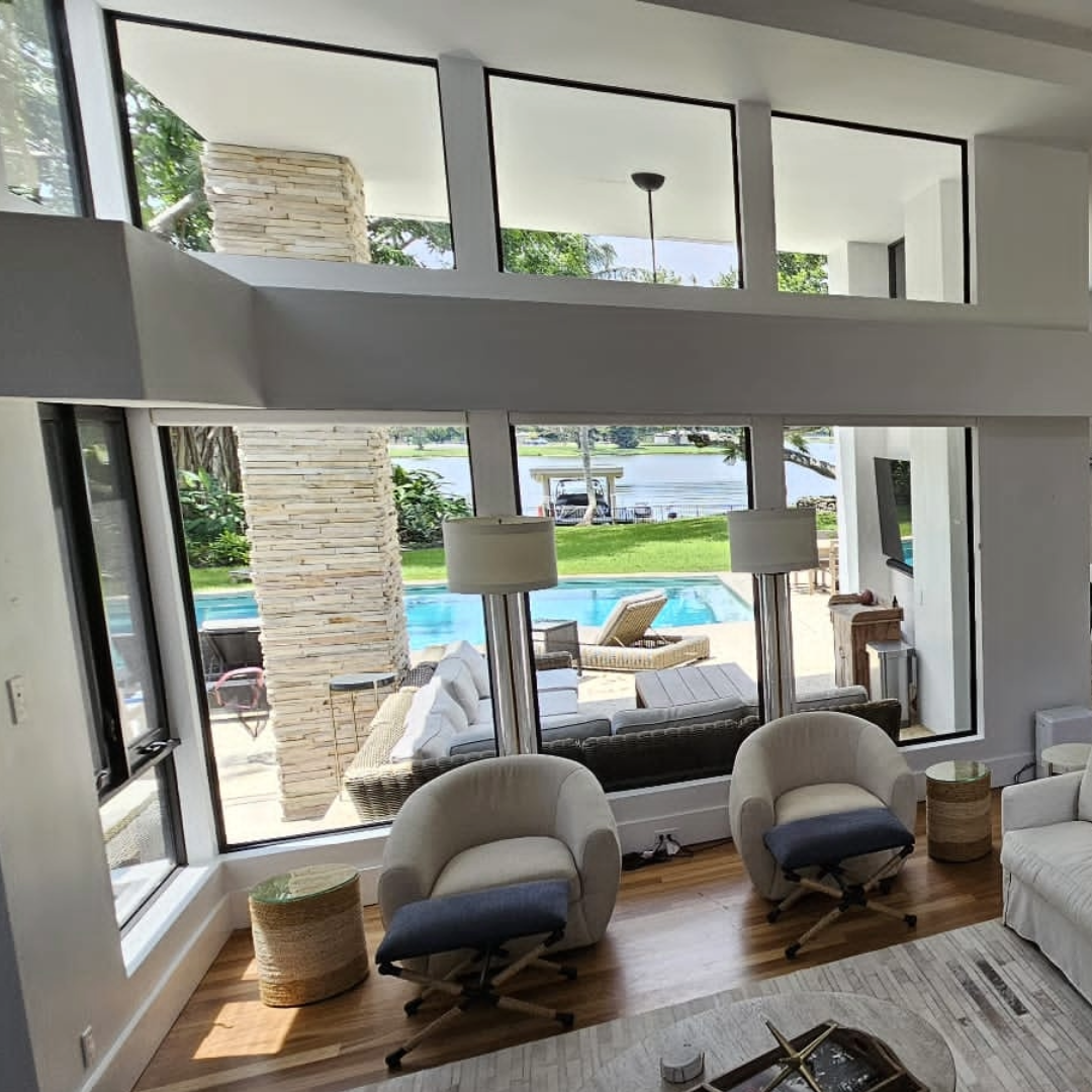 Modern living room with large windows overlooking a pool and garden window film used to not block the view with shades or blinds